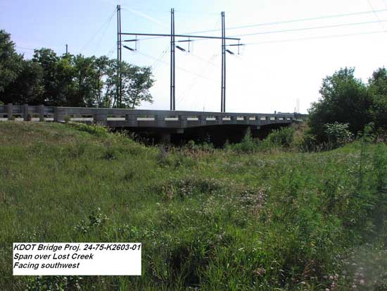 very shallow highway bridge over stream; power lines in background