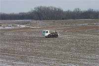 Vibroseis truck in field; light snow collects in furrows.