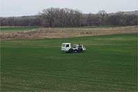 Vibroseis truck in field; strong green of wheat growing again.