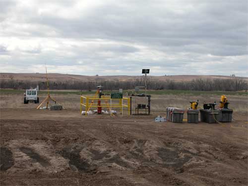 Overcast day; view of Murfin well site with cable storage cases in foreground; minivib truck in background