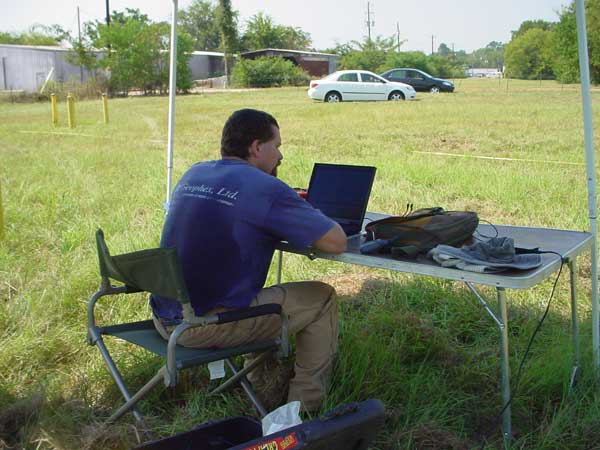 Worker with notebook PC at small table under tent.