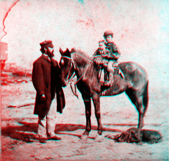 Bearded man, in hat, standing next to horse carrying young boy and infant ?girl?; dog laying on ground