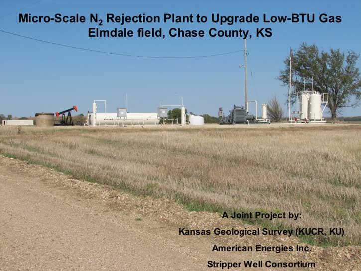 Overview of plant site; brown prairie grasses in foreground; single tree in background; tanks and processing equipment placed near oil pumpjack and tank.