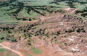 Photo from kite; red, eroded hills and gullies surrounded by green grass and brush.