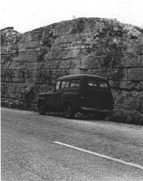 panel van parked next to 20-foot-high outcrop of limestone