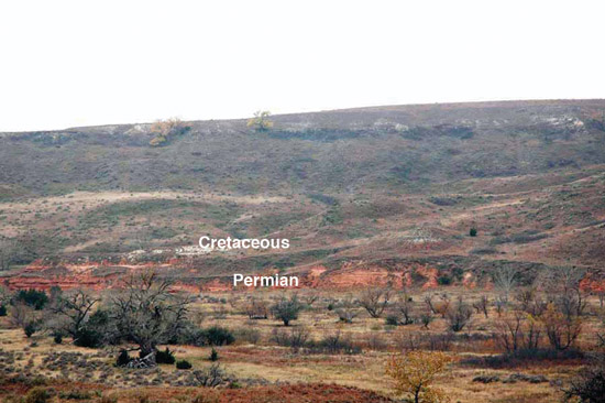 Color photo, Cretaceous-Permian contact just above stream bed below gentle hills.