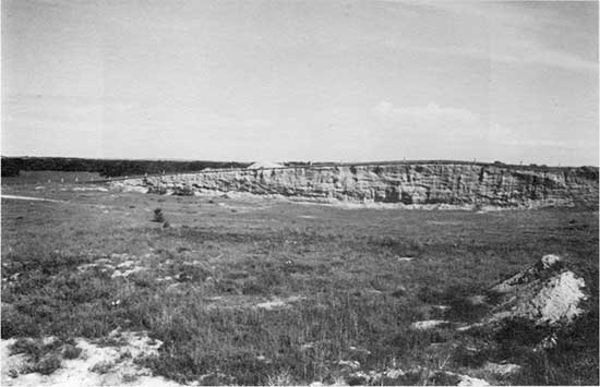 Black and white photo of T-4 terrace exposed in gravel pit as a low hill above the grasslands.