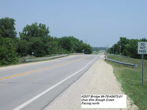 view along highway towards bridge; trees on either side