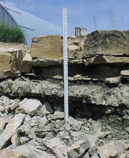 Top is tan-brown massive limestone of 1 ft thickness; middle is a persistant bed that is gray and more grainy, conglomeratic; middle is a shale eroded out.