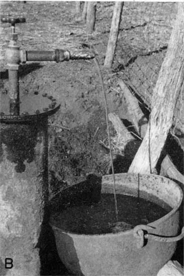 Black and white photo of water flowing into bucket; well topped by spigot.