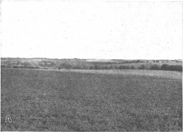Black and white photo of gently rolling hills; small stream in background.