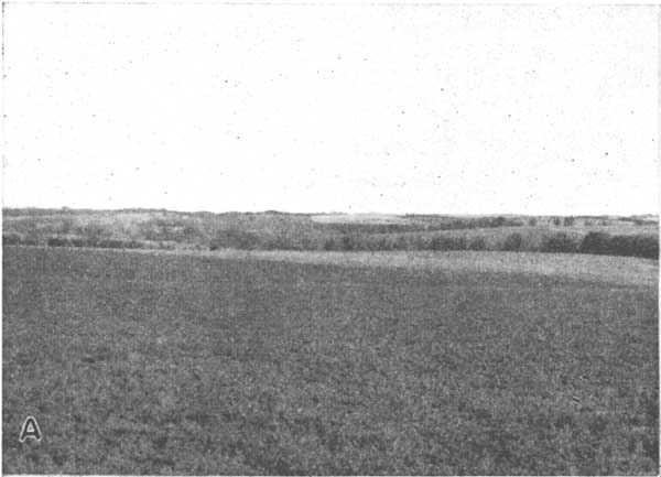 Black and white photo of gently rolling hills; small stream in background.