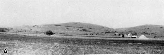 Black and white panorama of rounded hills above flat plain.