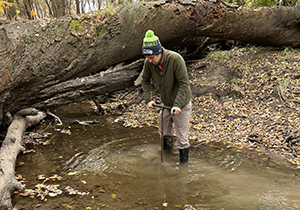 Sam Zipper installing a streambed sensor