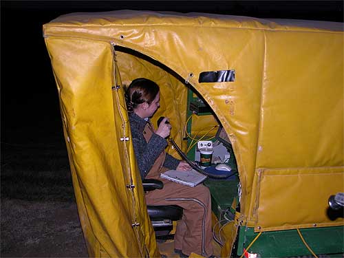 Technician in Green ATV with yellow cold-weather cover; speaking on radio