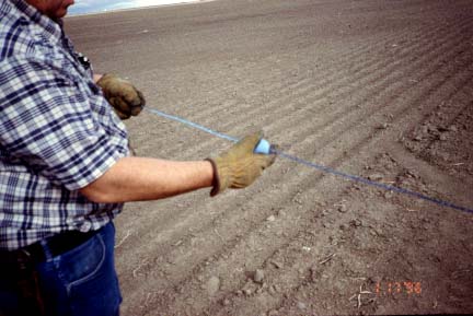 Photo shows worker applying blue carpenter chalk to metal measureing tape.