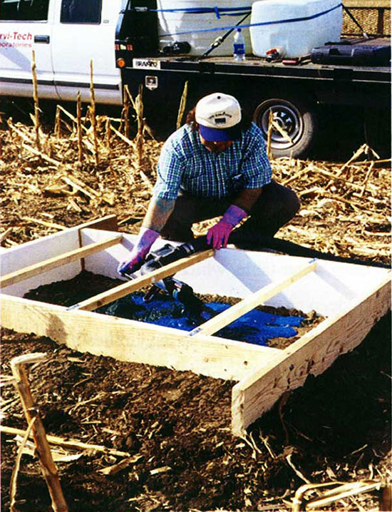 Worker with wooden frame filled with blue dye.