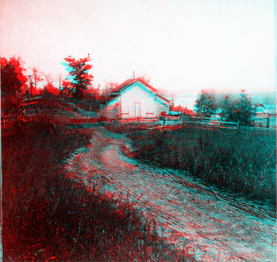 Dirt road leading to white barn and split-rail fence on hill above river