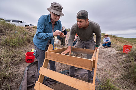 Laura Murphy and a field school student examine an artifact recovered from a test unit on Sand Creek at the Classen Ranch Locality in Meade County, Kansas.