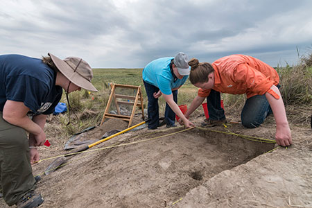 Odyssey crew member Paige Englert helps Washburn University field school students map the first level of their test unit.