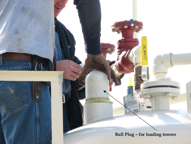 Loading of carbon in one tank is done; worker screwing on the plug to top of tank; plug is cylindrical, threded at bottom, spherical on top.