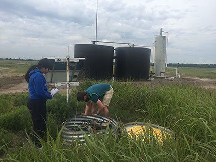 Undergraduate student, Zalma Molina and PhD candidate, Alex Nolte, service one of the stations near the Nelson tank battery in Wellington Field.
