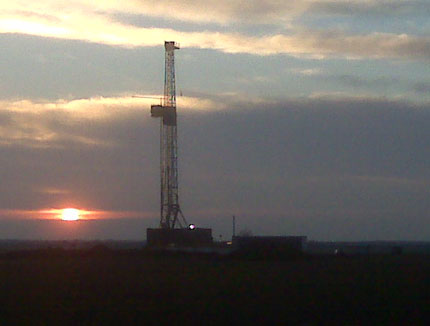 picture of drilling rig with sunset in background