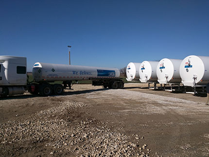 Shows a delivery truck from Woodward, OK, backing up to the left storage tank.