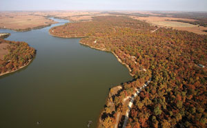 Photo from kite; view of trees in fall color around lake.