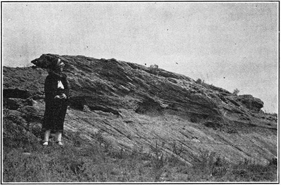 Black and white photo of woman standing next to outcrop of Ogalalla formation.