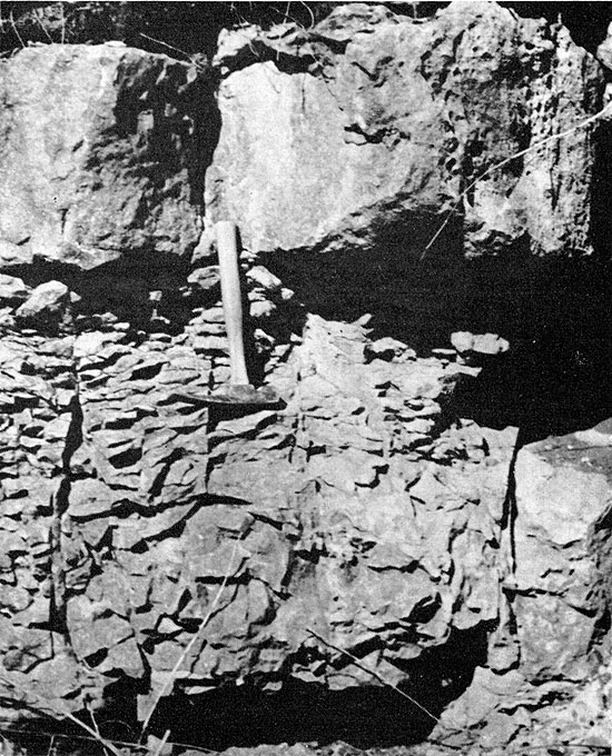 One black and white photo of Breezy Hill Ls, blocky at top (above rock hammer) and very broken up at base.