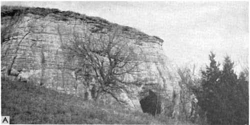 Black and white photo of outcrop; small cave in side of very steep hill.