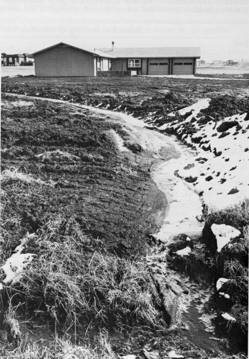 Photo of home at top of slope with curved drainage flowing around yard.