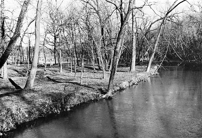 Slow moving stream just a foot or two below flat landscape.