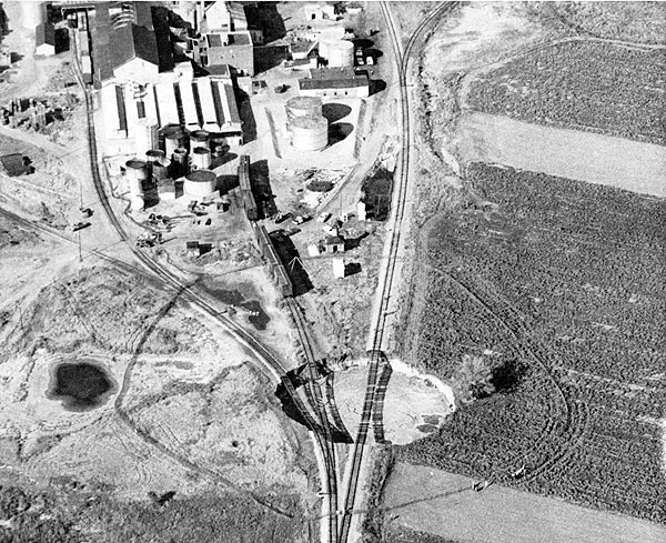 Photograph from air of sinkhole; train tracks suspended in air above hole, which has steep sides.