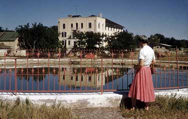 springs is a round walled-in pool surrounded by a decorative iron fence.  Stone buildings in background.