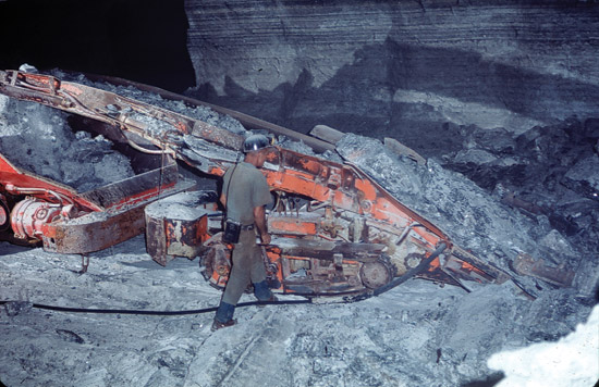 Color photo of salt miner and machine removing salt blocks from mine.