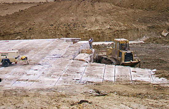 Color photo of limestone quarry; cut blocks being moved by heavy equipment.