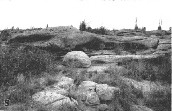 Black and white photo of smoothly eroded sandstone; some large rounded boulders; other parts massive but rounded with cave-like eroded areas.
