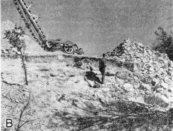 Black and white photo of quarry with man observing trenching machine.