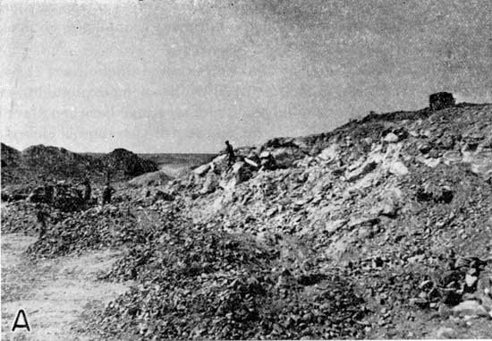 Black and white photo of Ogallala exposed in quarry, man for scale.