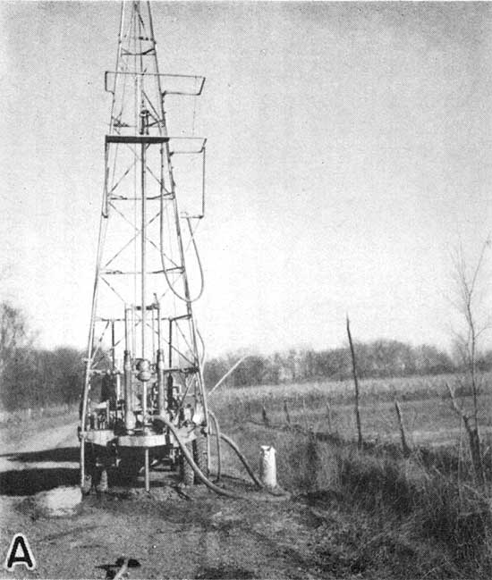 Small rig located off side of gravel road next to field.