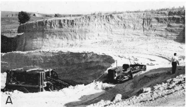 Bulldozer on curved road in mine below vertial face of exposure.