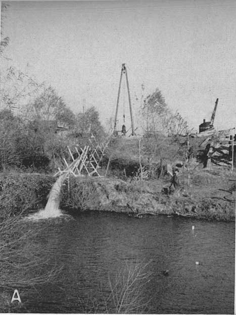 Black and white photo showing water pouring into river.