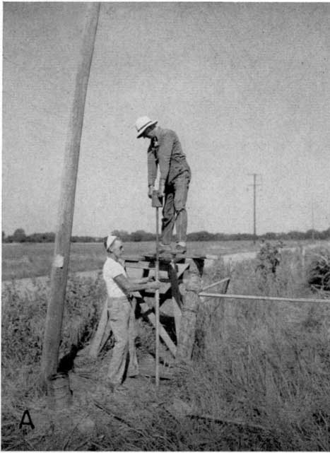 Black and white photo, man on 4-5-foot-tall platform hand driving a well.