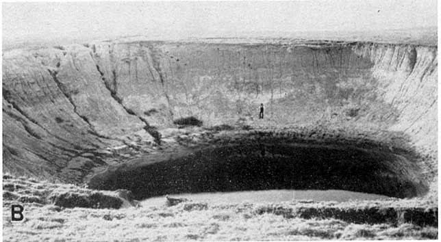 Black and white photo of sinkhole, partially filled with water.