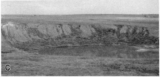 Black and white photo of sinkhole, partially filled with water.