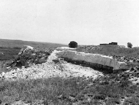 Black and white photo small quarry, bright white outcrop with darker gray layer beneath.