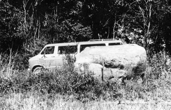Black and white photo of van parked next to Sioux quartzite boulder.