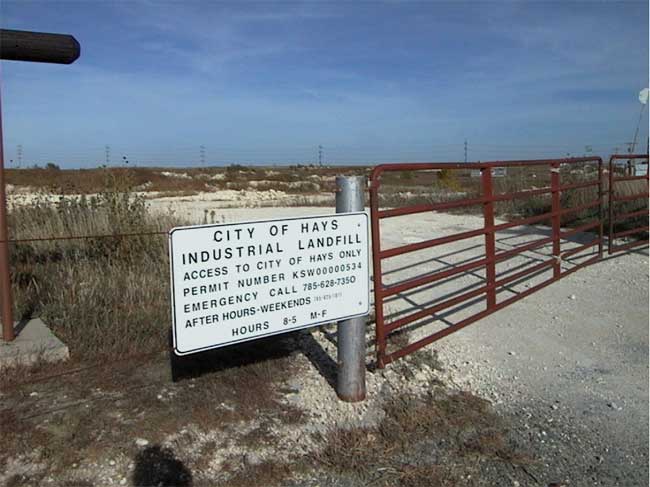 color photo of landfill entrance, metal gate and fence